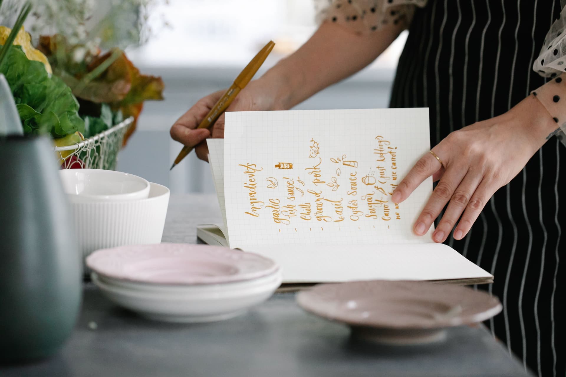 A person reading handwritten notes beside jars on a kitchen worktop