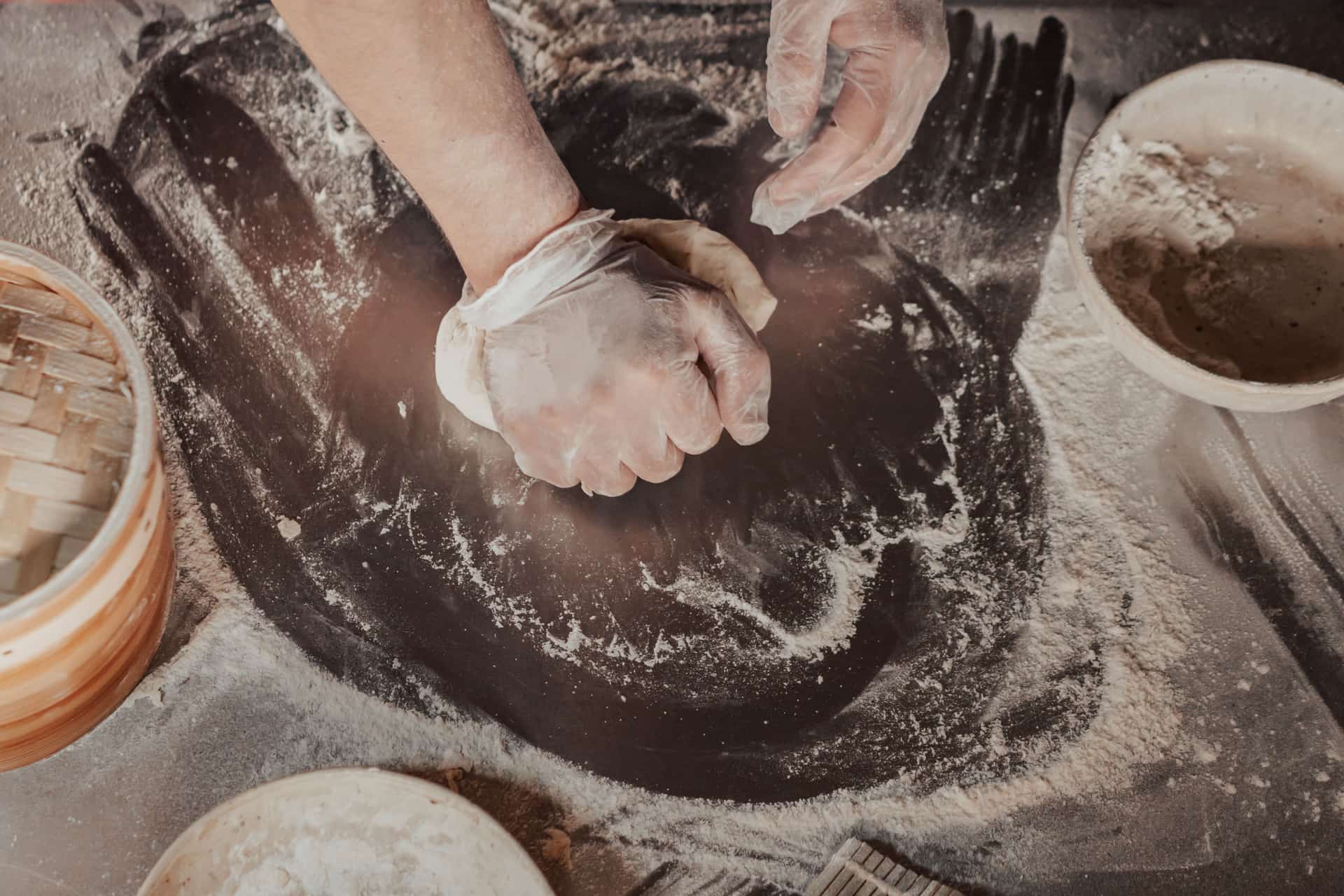 Hands kneading dough on a heavily floured work surface