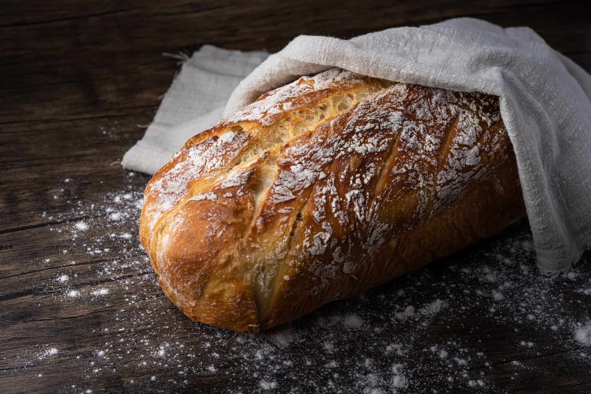 A rustic loaf partly covered with a cloth and dusted with flour