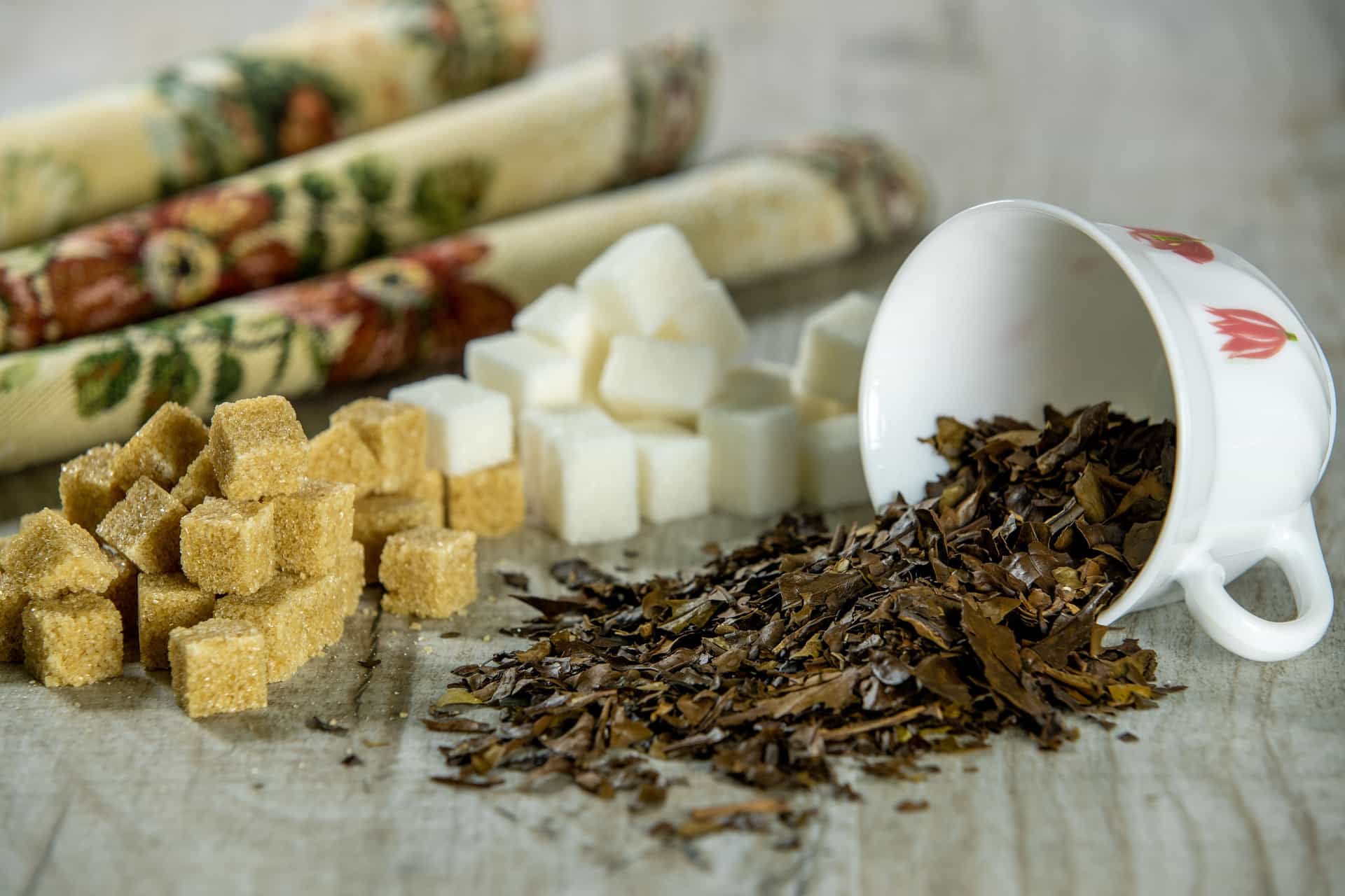 Loose black tea leaves and sugar beside a brewing vessel