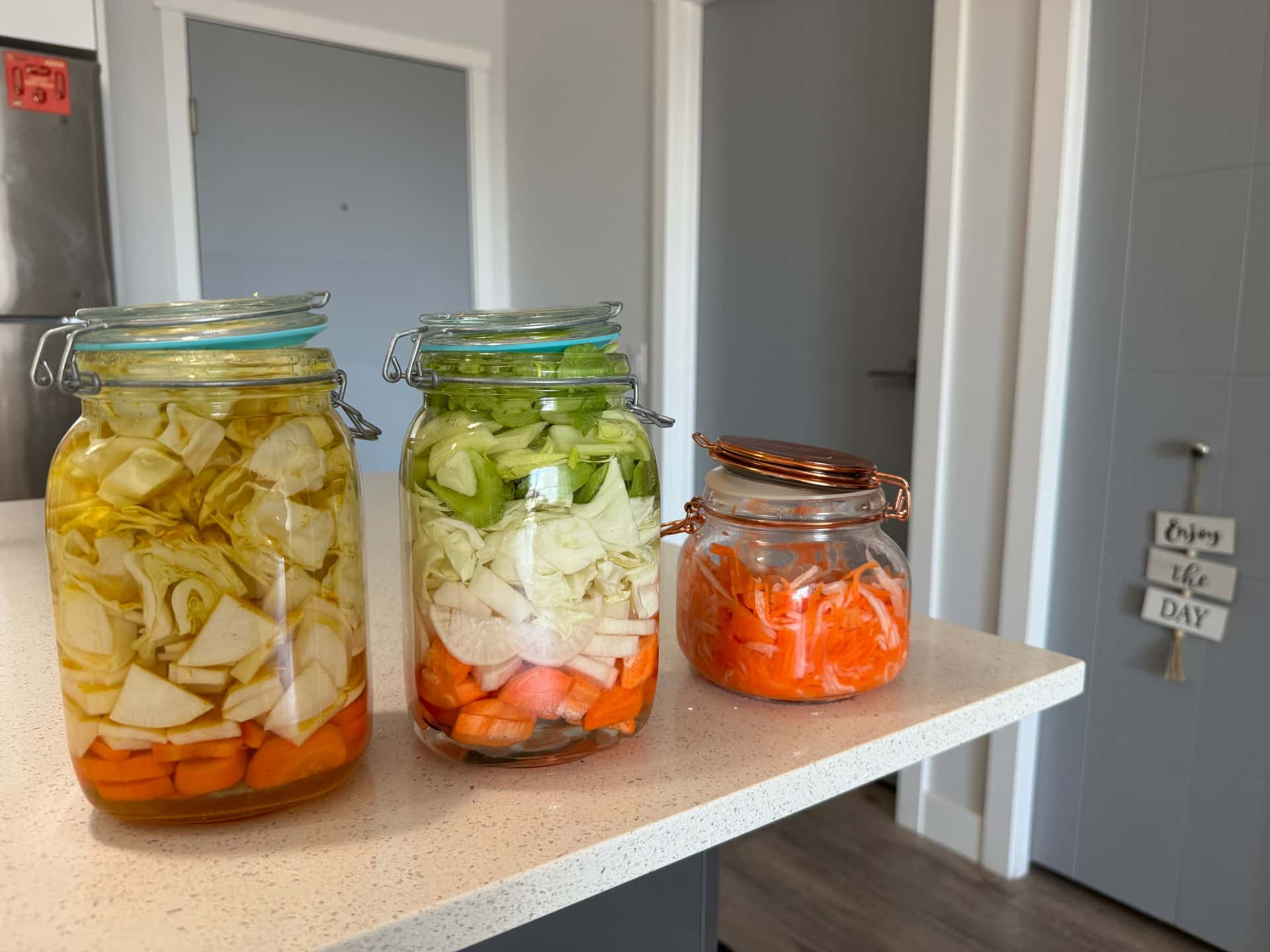 A glass jar packed with shredded cabbage in brine on a counter