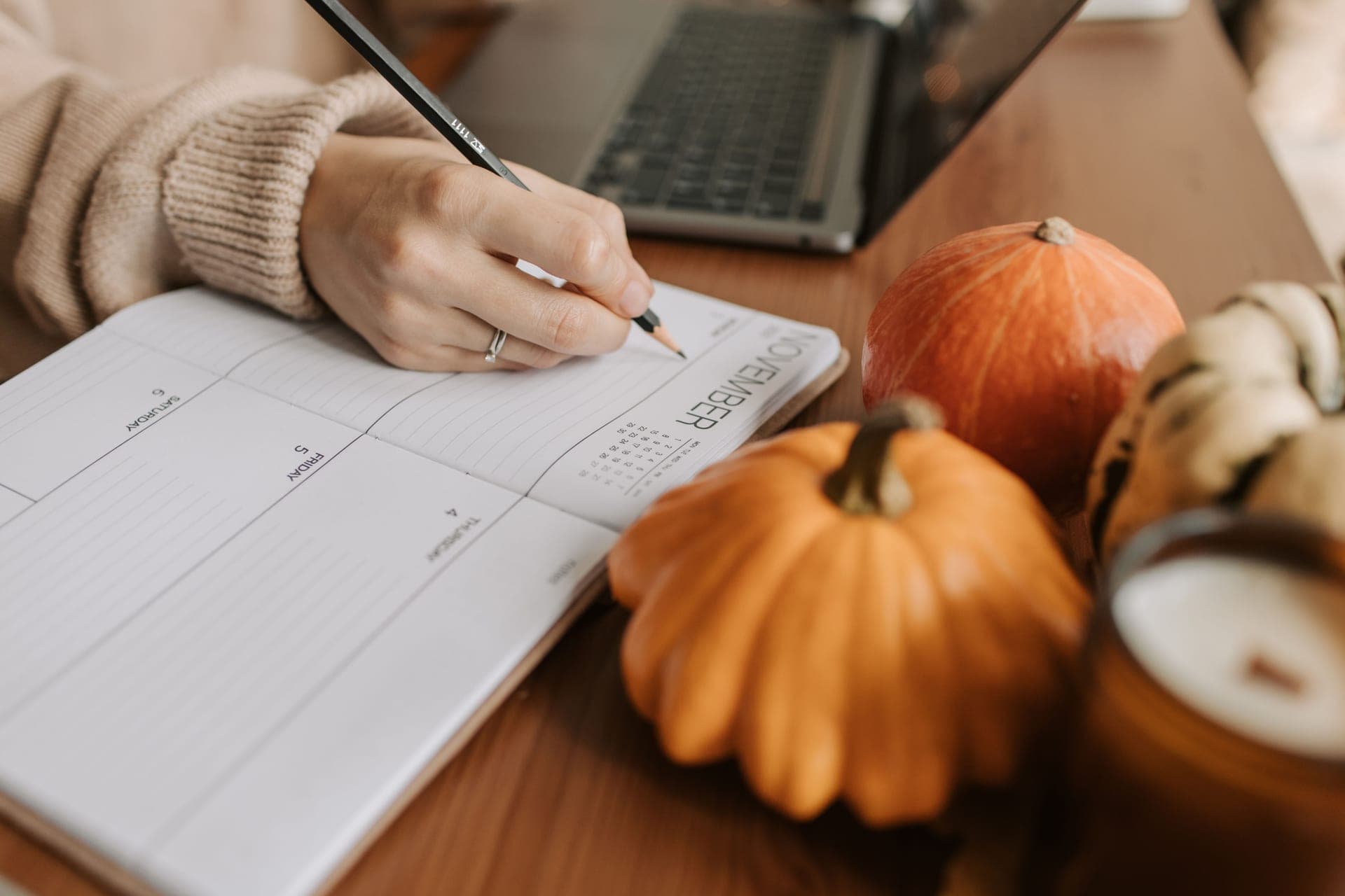 An open notebook and pencil beside a jar on a kitchen worktop