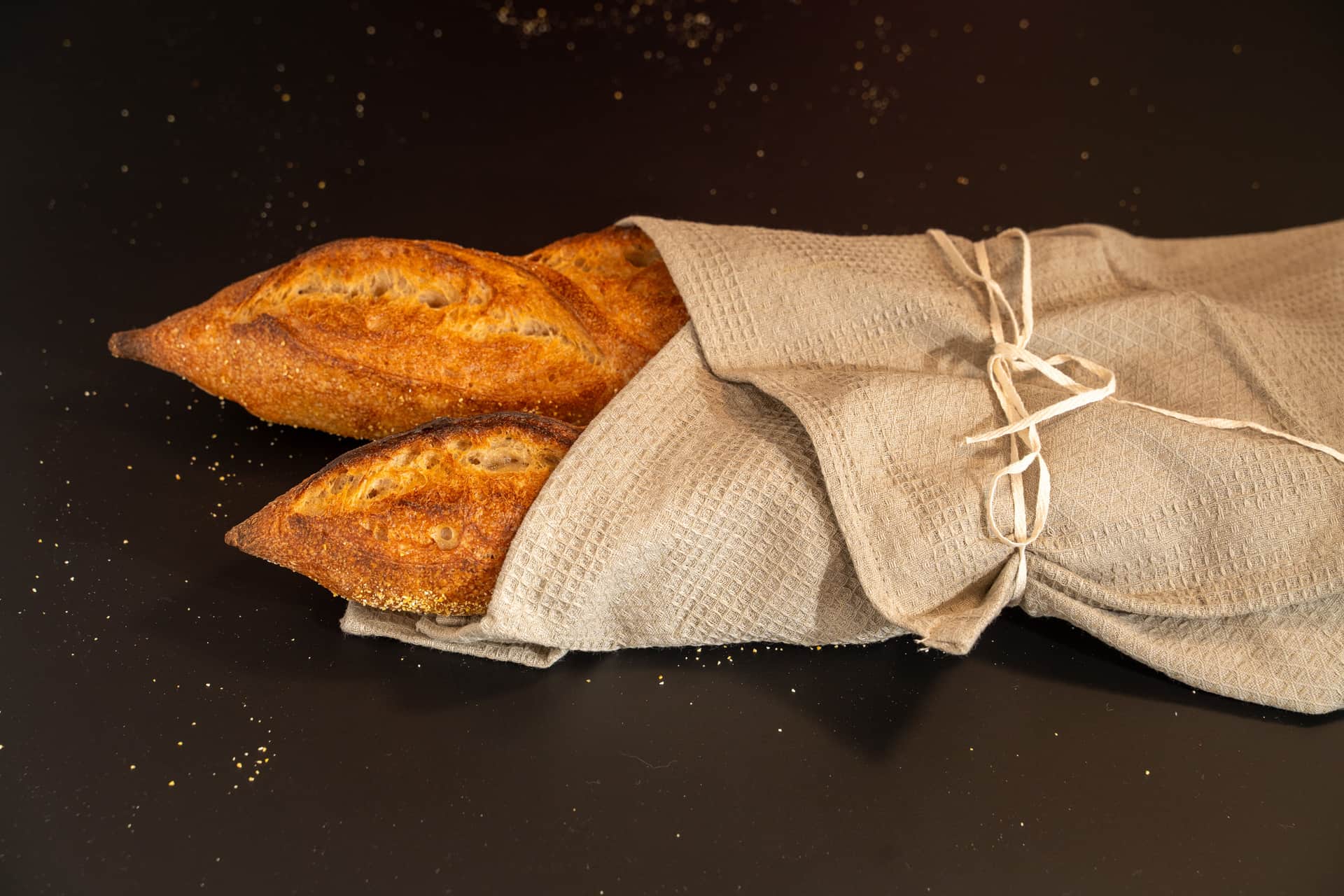 Two freshly baked baguettes wrapped in a linen cloth