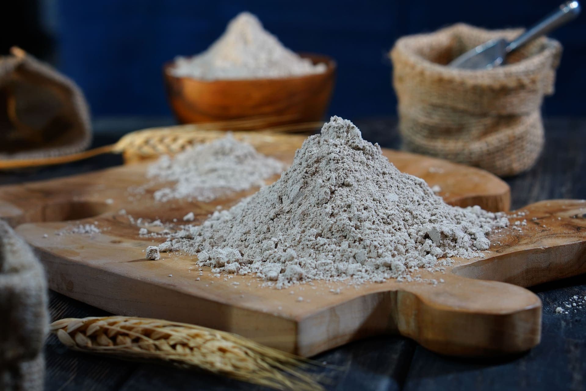Freshly milled flour and whole grains scattered together on a wooden board