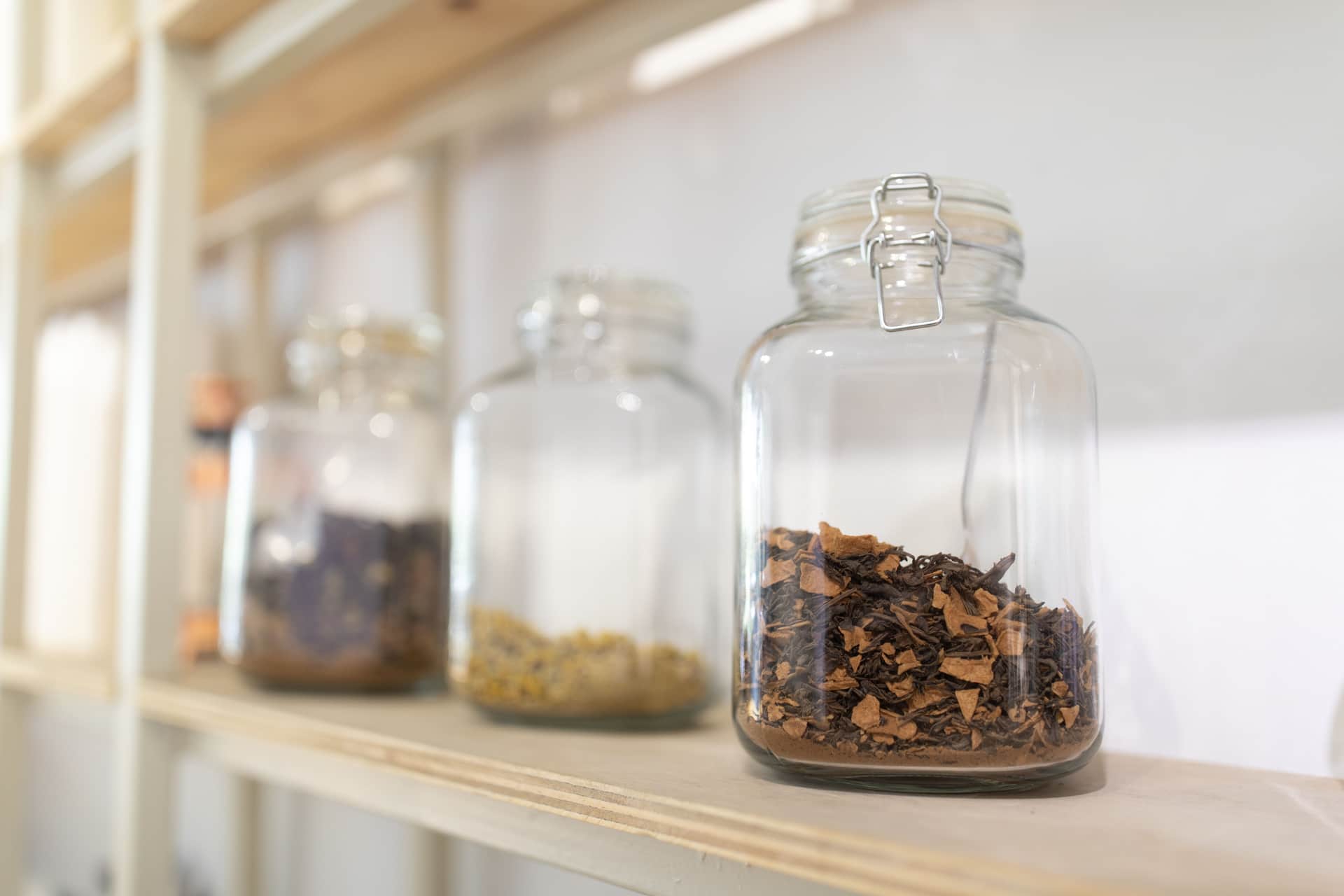 Glass storage jars in several sizes on a wooden kitchen shelf