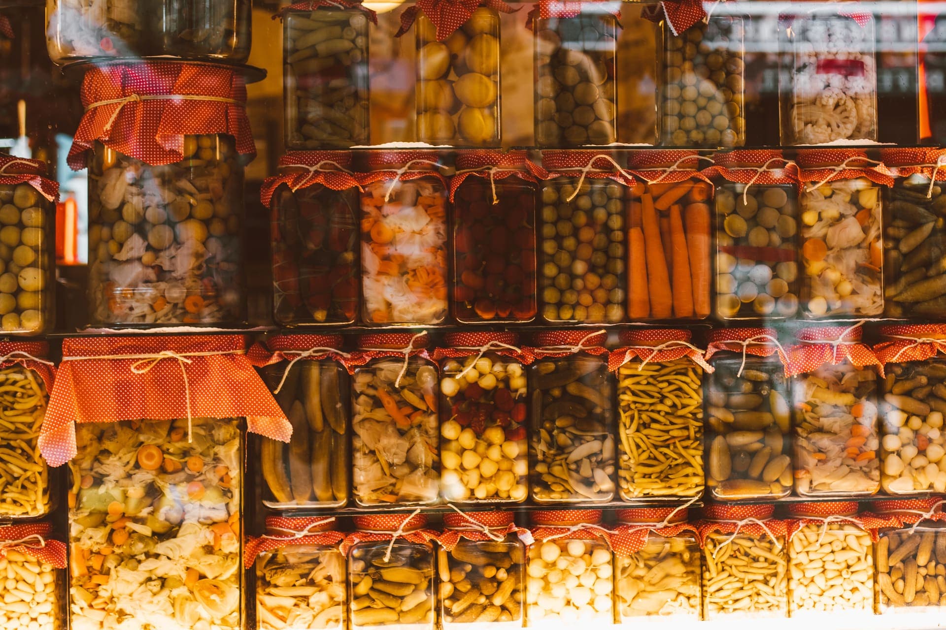 Rows of preserved vegetables in glass jars on a shelf