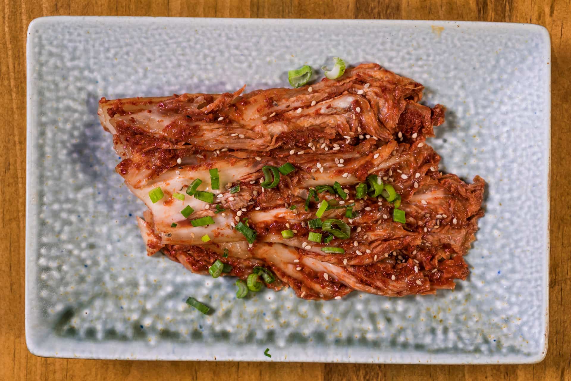 Close-up of freshly made kimchi with green onion and sesame on a textured plate