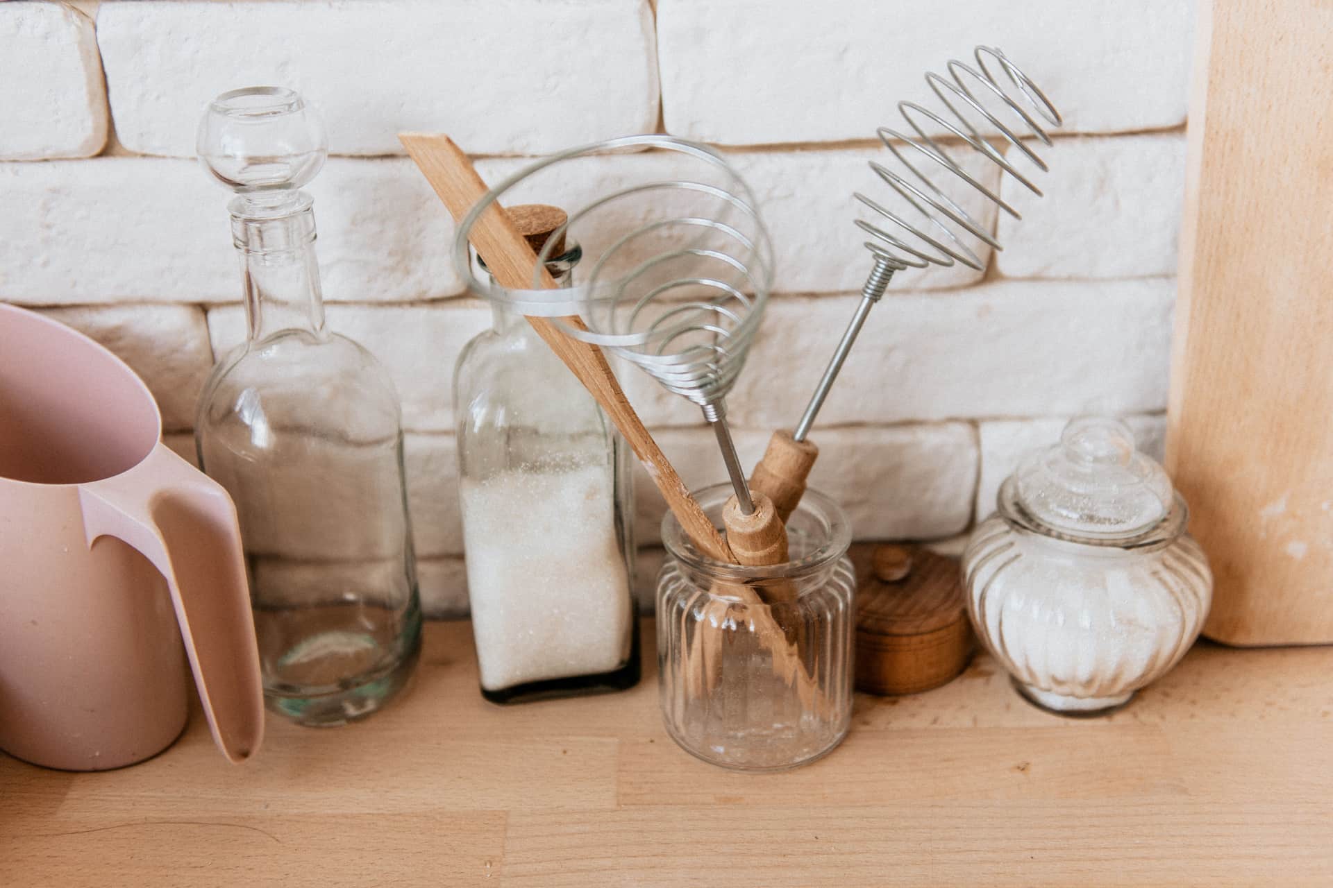 A collection of glass jars and kitchen utensils on a wooden counter