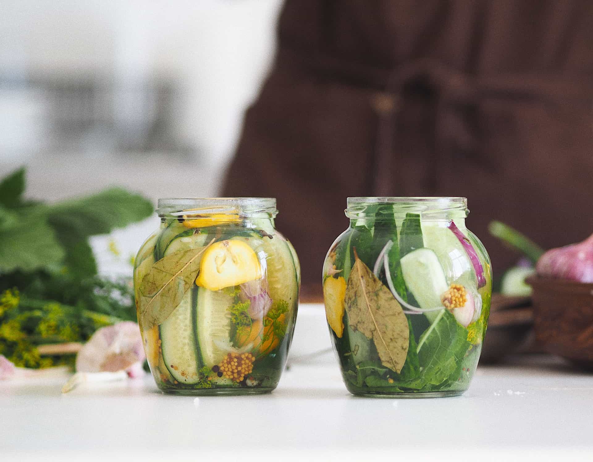 A jar of pickled cucumbers beside a bottle of vinegar