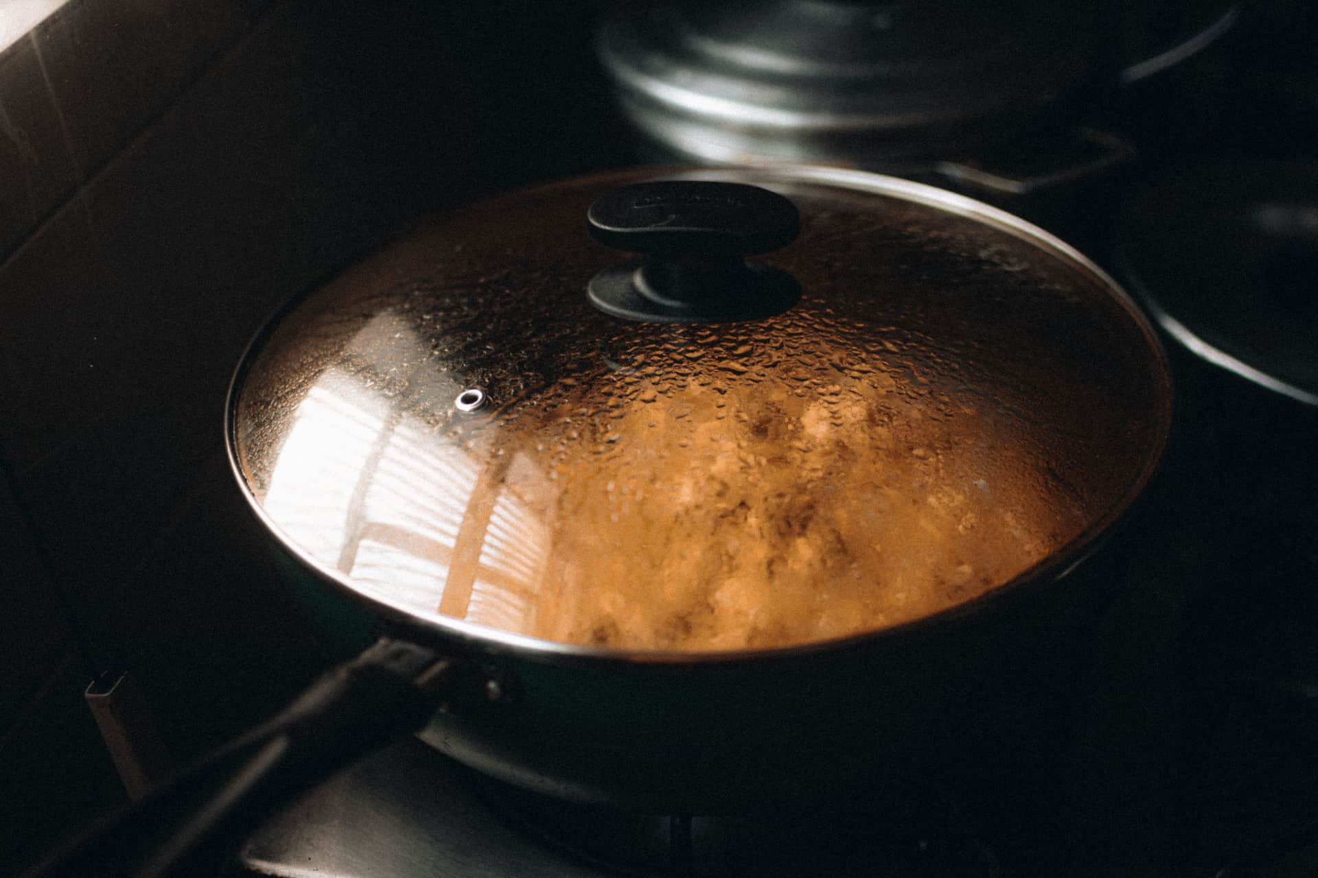 A steaming lidded pan on a stovetop