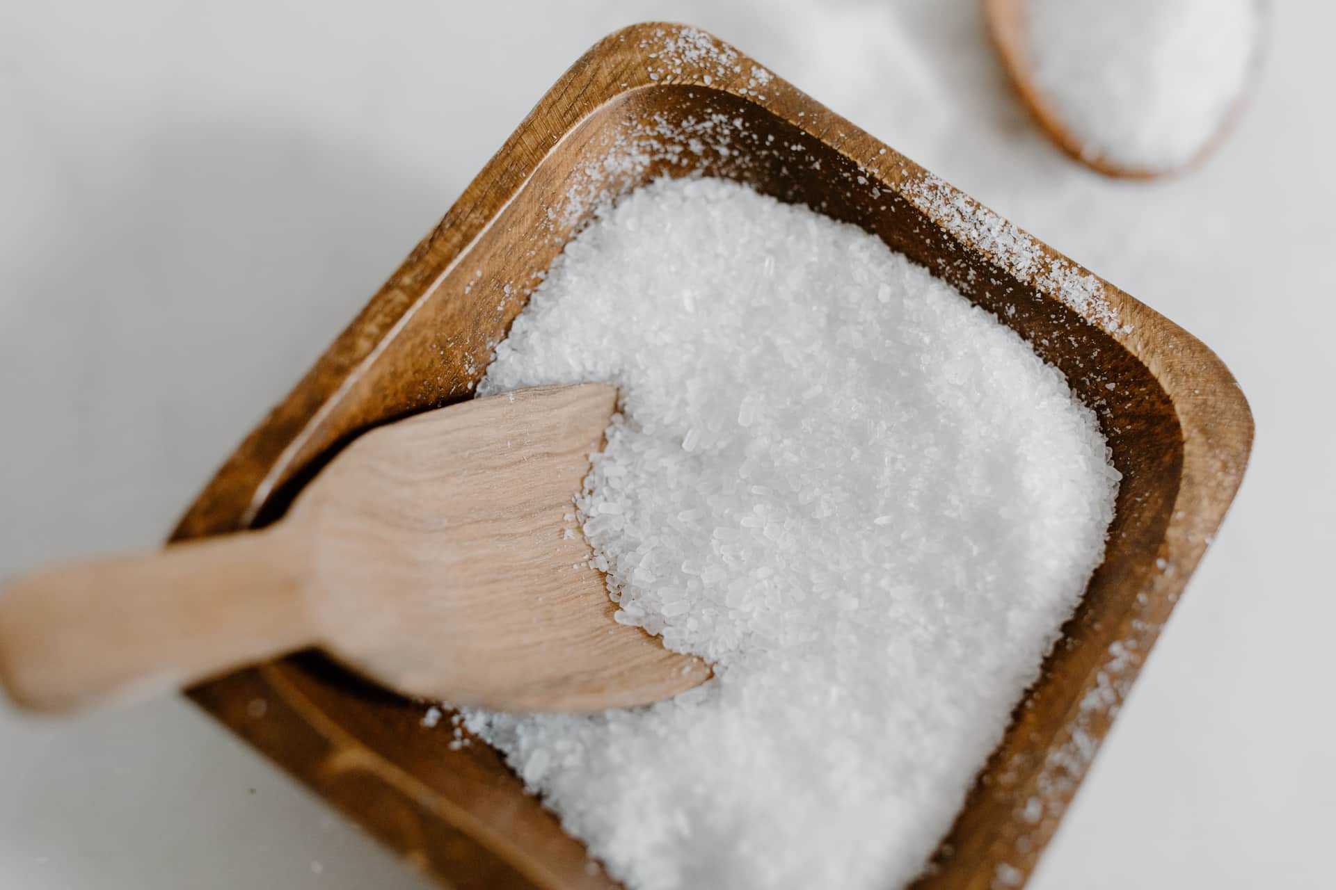 Coarse sea salt in a wooden bowl with a wooden scoop