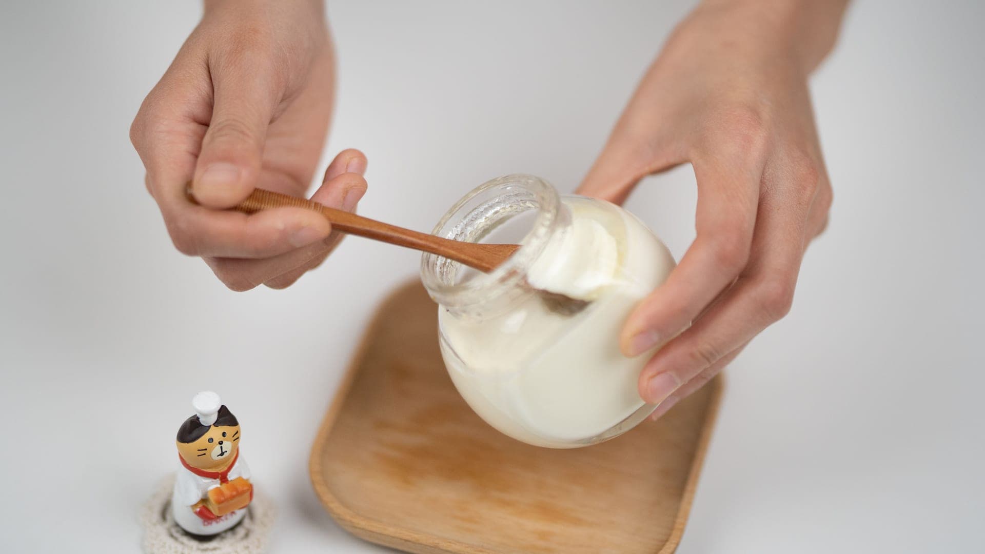 Small glass jars of homemade yogurt on a kitchen counter with a spoon